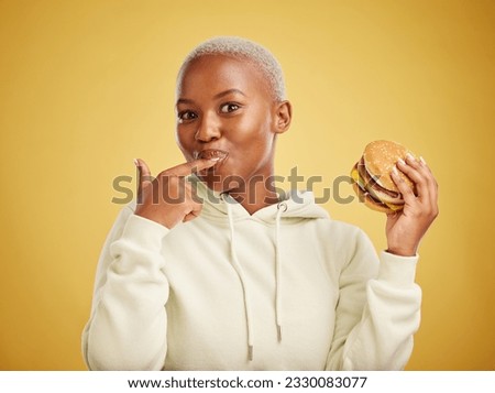 Burger, eating and portrait of woman or student on studio yellow background for restaurant promotion or deal. Hungry and happy, african person or customer experience with fast food or hamburger taste