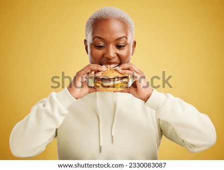 Burger, eating and woman or happy student on a studio, yellow background for restaurant promotion or deal. Hungry and excited african person or customer experience with fast food and hamburger bite
