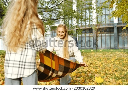 Family arranging picnic blanket in sunny autumn park. Horizontal photo