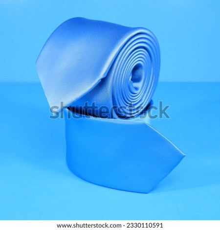 plain neck ties rolled together isolated over blue background closeup shot noperson 