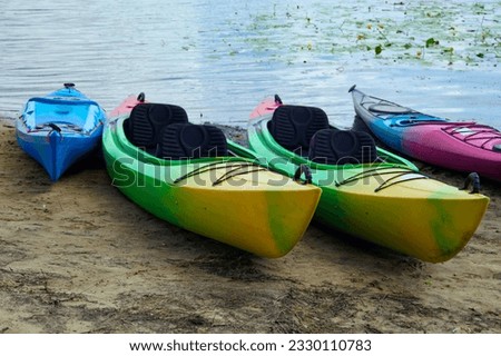 Landscape view of several colorful kayaks at the river shore. Boats on the city sandy beach, Obolon, Kyiv, Ukraine. Colorful kayaking equipment on a sandy beach. Royalty-Free Stock Photo #2330110783
