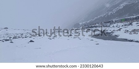 A picture of a snowy mountain during snowfall. 