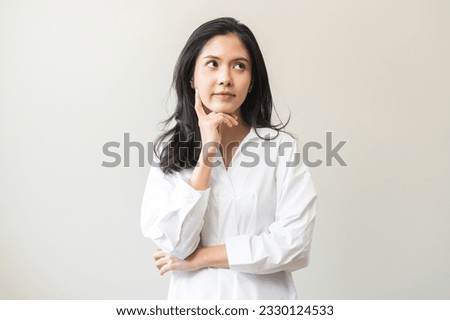Portrait of positive thoughtful asian young woman, girl keeps hand on chin looking away in white shirt casual, adult female thinking creative, thinks about future person, isolated on white background.