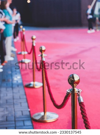 Red carpet with ropes and golden barriers on a luxury party entrance, cinema premiere film festival event award gala ceremony, wealthy rich guests arriving, outdoor decoration elements, summer day Royalty-Free Stock Photo #2330137545