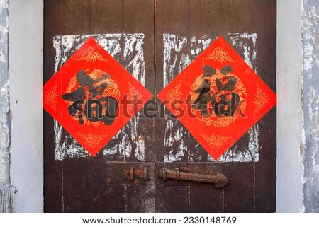 Two red Chinese blessing "Fu" (it means luck and prosperity) for Chinese new year replaced the old ones for the New Year on the traditional chinese wooden door Royalty-Free Stock Photo #2330148769