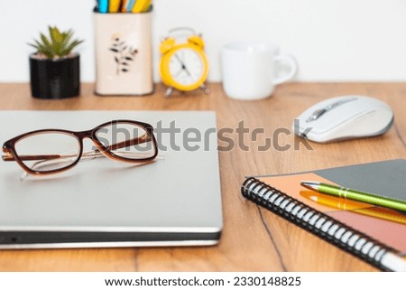 the closed notebook computer was placed on the desk in the room, women's glasses put away