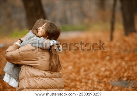 Mother and her daughter hugging in autumn forest
