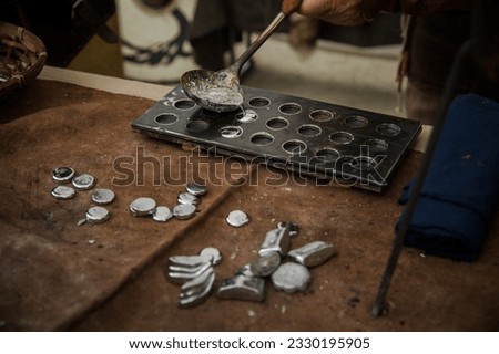 A person pouring molten metal into a mold to create Roman coins, capturing the ancient art of coin making.