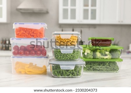 Glass and plastic containers with different fresh products on white marble table in kitchen. Food storage Royalty-Free Stock Photo #2330204373