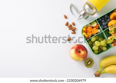 Showcase school lunch experience with a top-down image of lunchbox brimming with sandwiches, nutritious fruits, veggies and water bottle on white isolated background, offers space for text or adverts Royalty-Free Stock Photo #2330206979