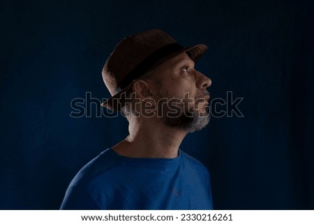 Portrait of bearded man wearing hat posing for photography. Isolated on blue background.
