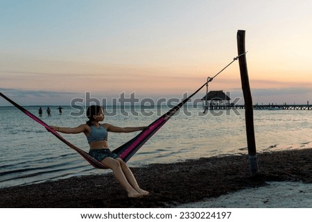 Young girl sitting on a hammock at a beach during sunset on summer break 