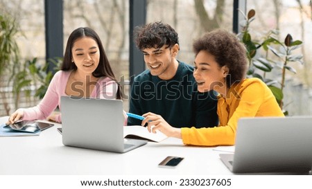 Happy international students friends sitting at desk in coworking space and using laptop, making project together or watching educational video, panorama Royalty-Free Stock Photo #2330237605