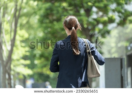 A Japanese woman in a suit standing in the fresh green Royalty-Free Stock Photo #2330265651