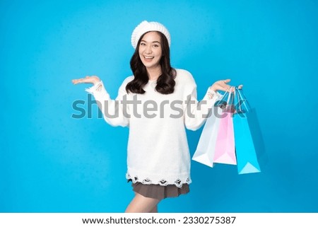 sian female seller, long hair, bright smile, is an online seller. holding several shopping bags to prepare to buy goods, wearing a hat and a white dress, taking pictures in a blue scene in the studio