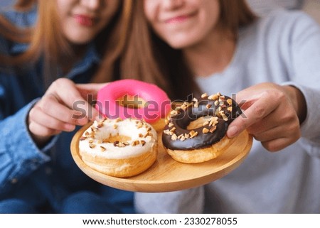 Closeup image of a young couple women holding and eating donuts together Royalty-Free Stock Photo #2330278055