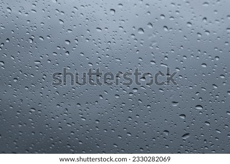 Rain drops on blue glass background. Bokeh street light out of focus autumn abstract backdrop.