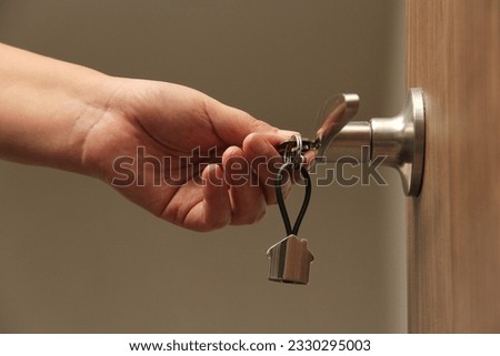 Keys with keyring in the shape of a house open door as a concept of real estate delivery of a new house and security at the entrance