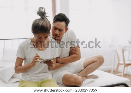 Asian husband peeking wife chatting on the phone if she might has an affair. Royalty-Free Stock Photo #2330299059