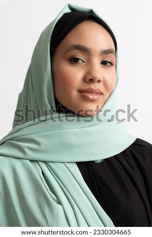 Close-up portrait of a smiling, beautiful Muslim woman with clean, smooth skin wearing a blue hijab 