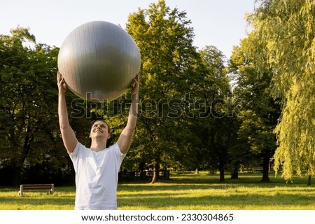 Man with fit ball fitness yoga outdoor. Sunny hot day.  the sunny morning. fit young man exercising outdoors in the park. Healthy and active lifestyle concept. Training out