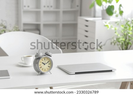 Alarm clock with laptop on table in office
