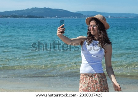 happy girl taking a selfie or direct video with phone on the beach