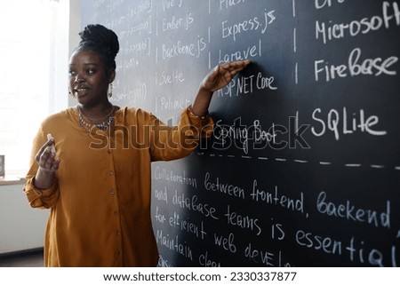 Young teacher teaching IT lesson Royalty-Free Stock Photo #2330337877
