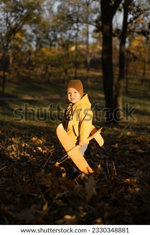 Child boy playing with an airplane in the autumn park. The concept of freedom and happy childhood. Copy space