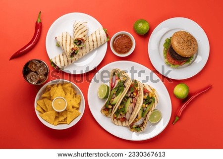 Mexican food featuring tacos, burritos, burgers and more. Flat lay over red