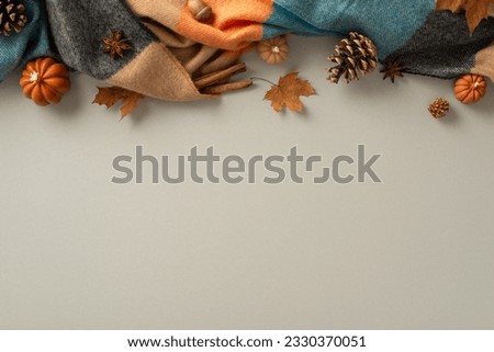 Fall into the comforts of home with this top view photo. Cozy patchy blanket, pumpkin candles, pinecones, odorous spices and maple leaves offer the perfect grey backdrop for text or advert