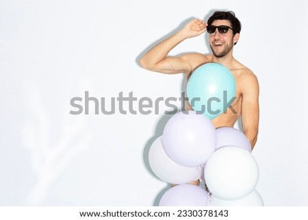 Caucasian Handsome Brunet Man With Bunch of Colorful Air Balloons in Hand While Posing in Underware Against White Background. Horizontal image Composition