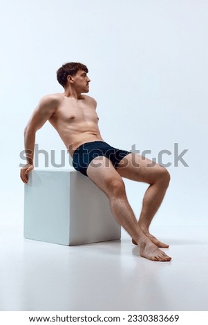 Full-length image of young man with muscular body posing shirtless in underwear against white studio background. Concept of man's beauty, sportive and healthy lifestyle, athletic body Royalty-Free Stock Photo #2330383669