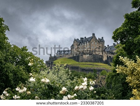 The Castle of Edinburgh up the Hill on a Cloudy Day Surrounded by Green Landscape as pictured from the City Centre of Edinburg, Scotland