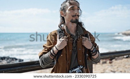 Young hispanic man tourist wearing backpack at seaside