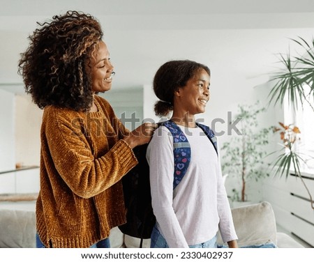 Mother helping daughter to get ready for school, helping her with backpack and books,hugging and leaving home  Royalty-Free Stock Photo #2330402937