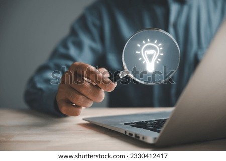 Businessman finds light bulb using magnifying glass. Idea and imagination. Concept of creative innovation. Innovation icon represents network connection. SEO enhances idea optimization.