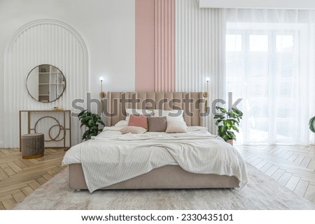 a soft bed in the bedroom by the window in a spacious open-plan apartment with a stylish modern bright design on a sunny day Royalty-Free Stock Photo #2330435101