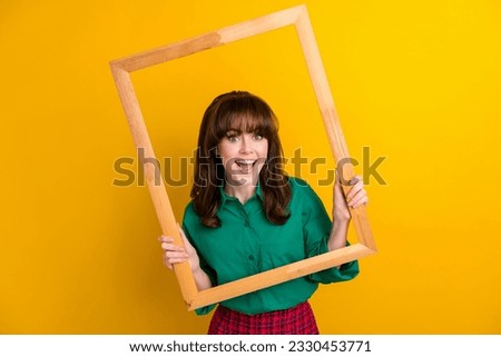 Photo of excited funky woman dressed green shirt tacking photo wooden frame isolated yellow color background