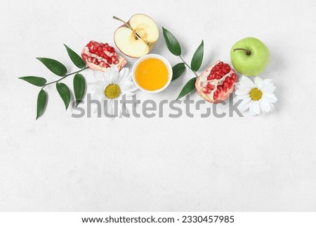 Composition with bowl of honey, ripe fruits, flowers and plant leaves on light background. Rosh hashanah (Jewish New Year) celebration Royalty-Free Stock Photo #2330457985