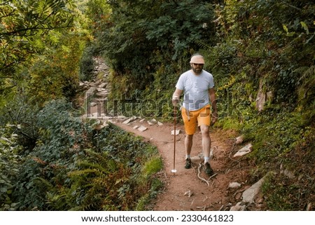 a hiker with stick is walking on a mountain trail high in the mountains