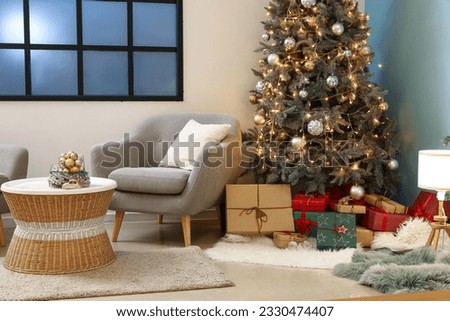 Interior of living room with Christmas tree, gift boxes and grey armchair