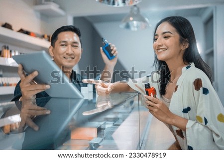 beautiful customer pointing on the digital tablet that showed by the male vape seller while trying the vape mods