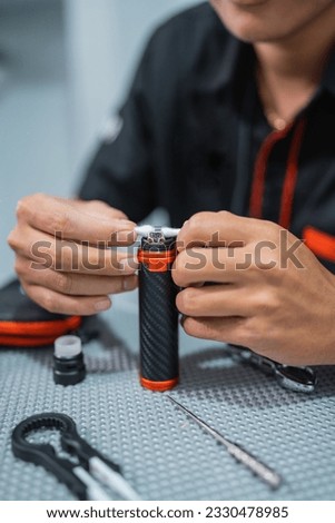 portrait of the male vape seller changing the cotton coils inside the vape mods
