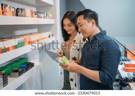 couple of shopkeeper checking the availability of liquid stock on digital tablet