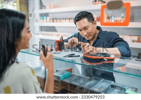 male vape shopkeeper changing the cotton coil while the female customer vaping in front of him
