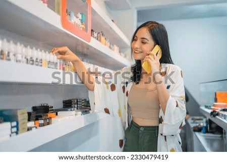 beautiful shopkeeper observing the liquid stock at the shelf while calling on phone