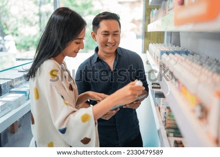 couple of shopkeeper observing the liquid together using the digital tablet
