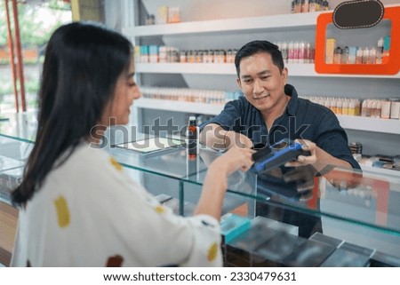 female customer paying the stuff using the credit card at the vape store