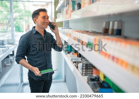 attractive vape shopkeeper holding the digital tablet with green screen while calling on phone